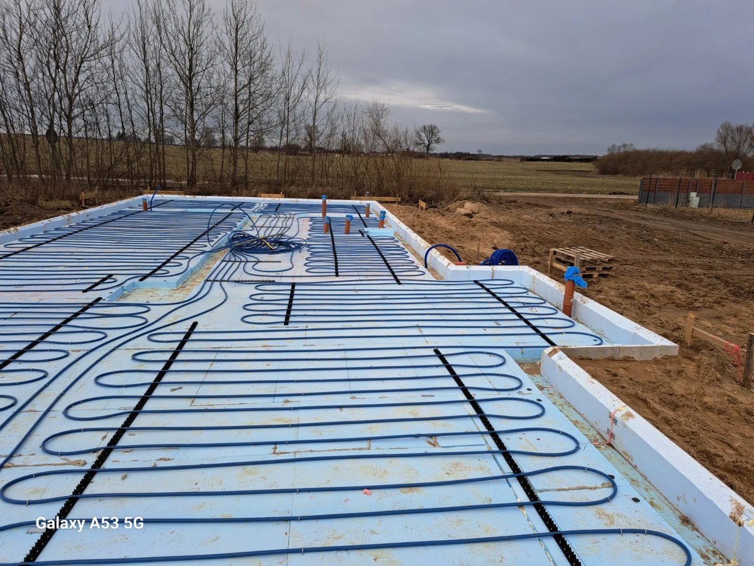 Instalacja wodnego ogrzewania podłogowego rozłożona na izolacji płyty fundamentowej przed betonowaniem